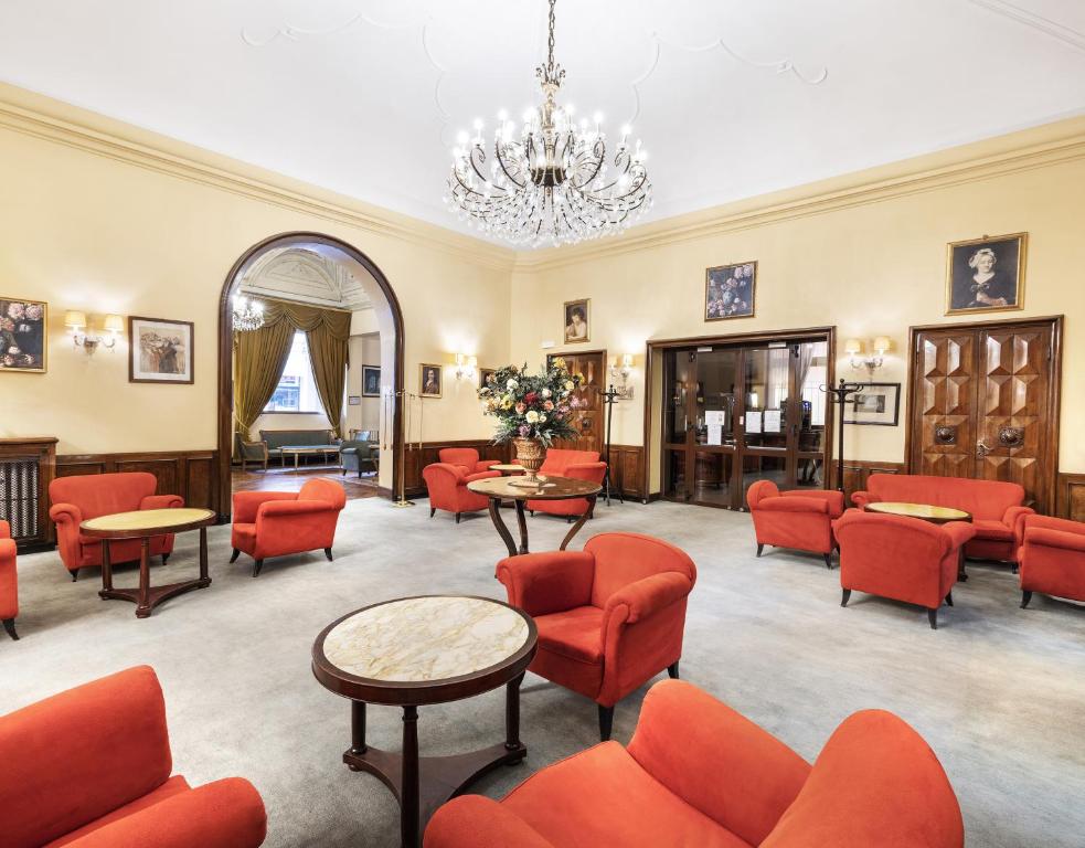博洛尼亚Hotel Palace Bologna Centro的一间设有红色椅子和桌子以及吊灯的等候室