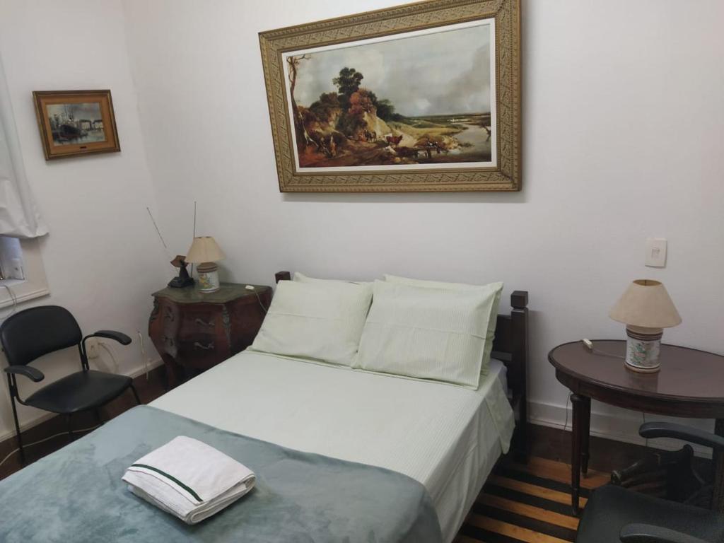 里约热内卢Estúdios Deluxe São Manuel的卧室配有一张床,墙上挂有绘画作品