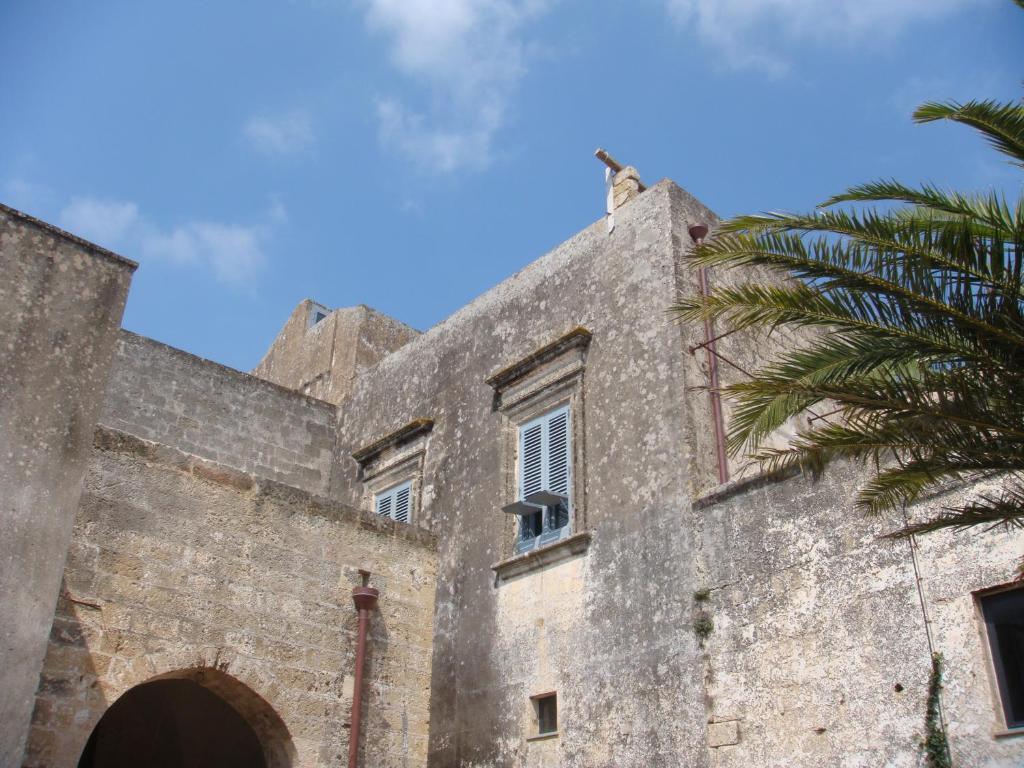 加利亚诺德尔卡波Castle XVIII near sea的一座古老的石头建筑,有棕榈树