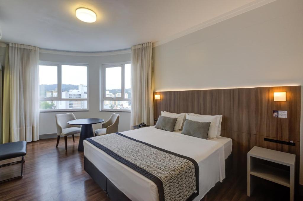 布卢梅瑙Slaviero Blumenau的酒店客房配有一张床铺和一张桌子。