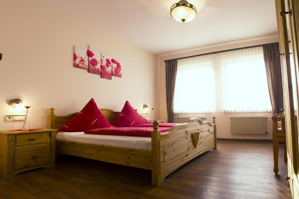 伦讷施塔特Pension Möser的一间卧室配有一张带红色枕头的木床。