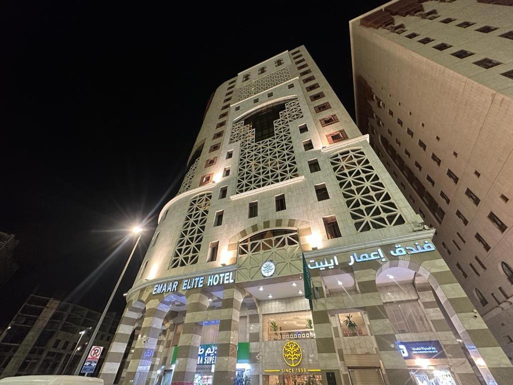 麦地那Emaar Elite Al Madina Hotel的一座高大的建筑,晚上有标志