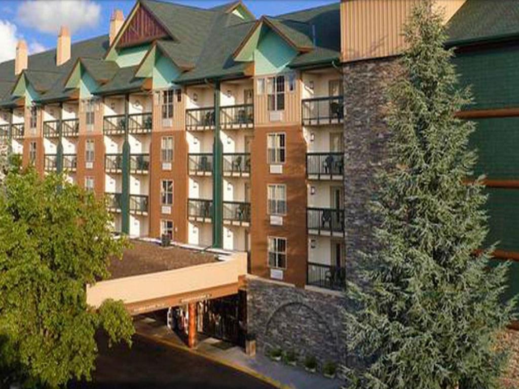 鸽子谷Grand Smokies Resort Lodge Pigeon Forge的一座大型公寓楼,前面有一棵树