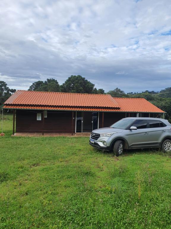 乌鲁佩马Casa p fim de semana p 6 pessoas 12km, do centro de urupema的停在房子前面的田野上的汽车