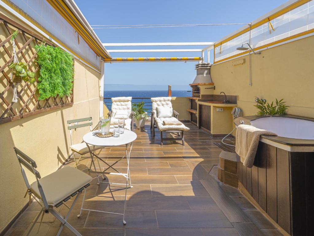 坎德拉里亚EDEN RENTALS Caletillas Ocean Views的阳台配有浴缸和桌椅。