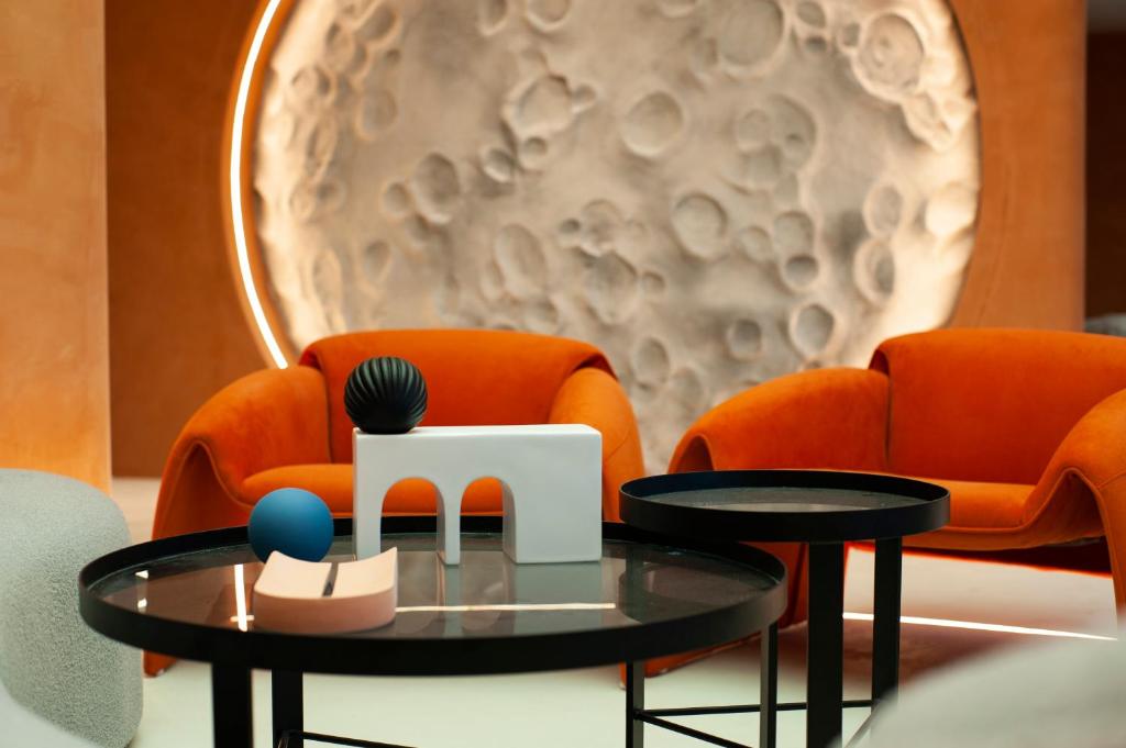 西安忆宿石玖设计师酒店(西安钟鼓楼回民街店)的两把橙色椅子前的茶几