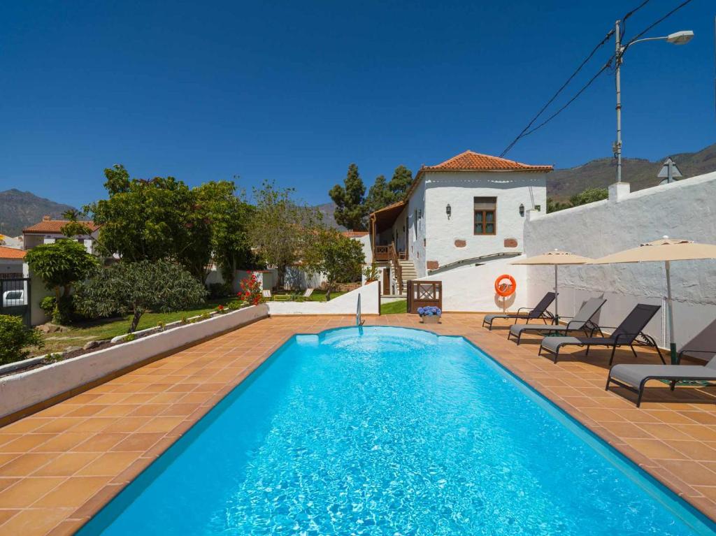 圣卢西亚Casa Rural la Montañeta的一个带椅子的游泳池以及一座房子