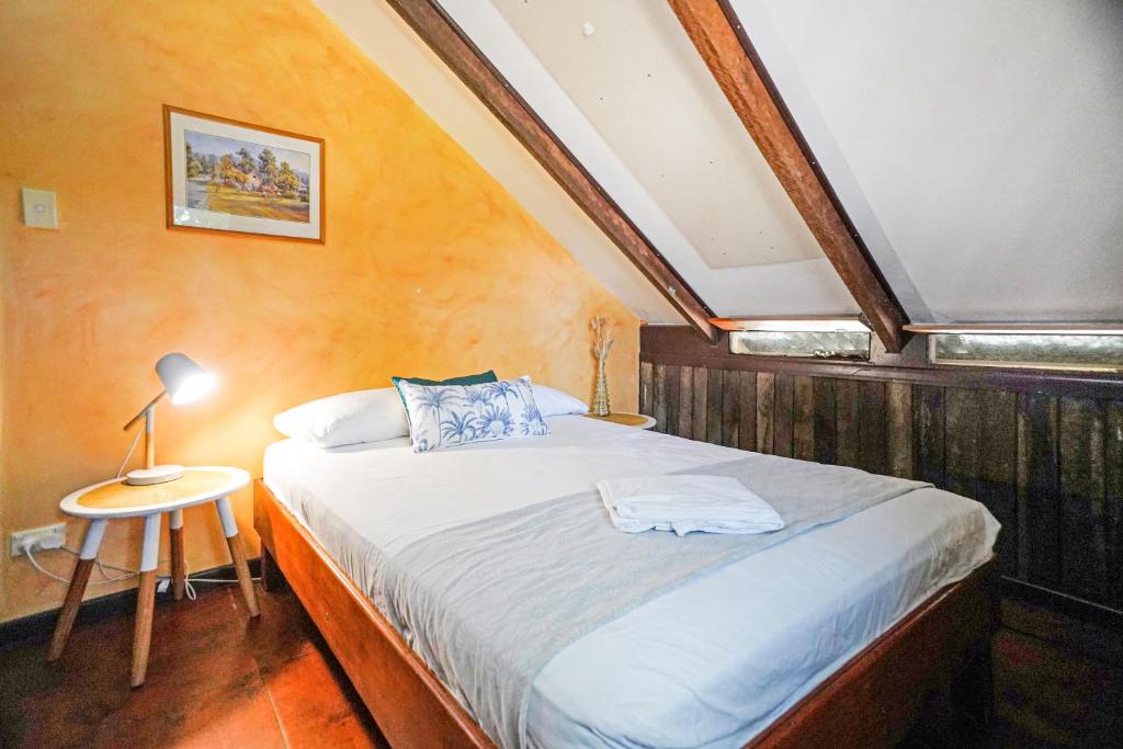 赫维湾Woolshed Eco Lodge的一间卧室配有一张床和一张带台灯的桌子