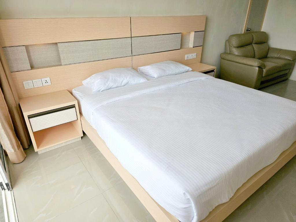 名古屋Nagoya thamrin apartment (Favehotel Building)的一间卧室配有一张大床和一把椅子