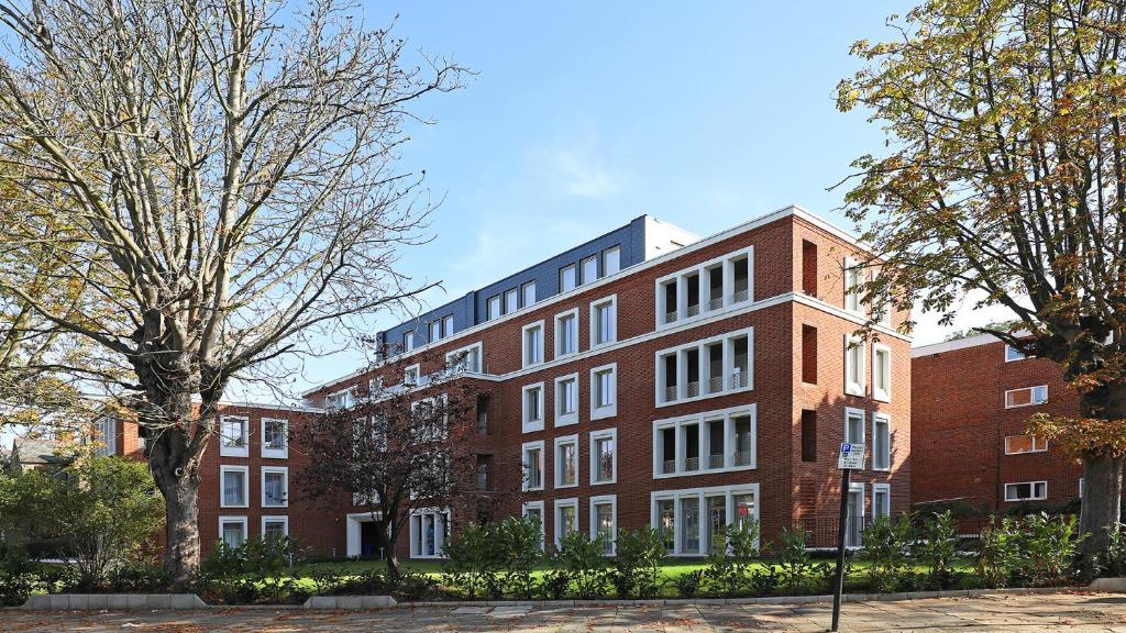 伊灵Stunning apartment building, walking distance to Ealing Broadway tube!的前面有树木的红砖建筑