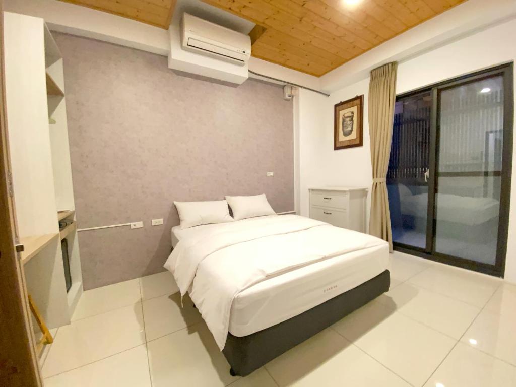 台南108巷会馆的卧室配有白色的床和空调