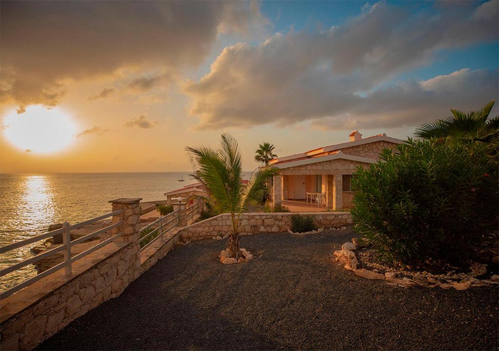 马约城Villa Lagosta Stella Maris Exclusive的海滩上的房子,背景是日落