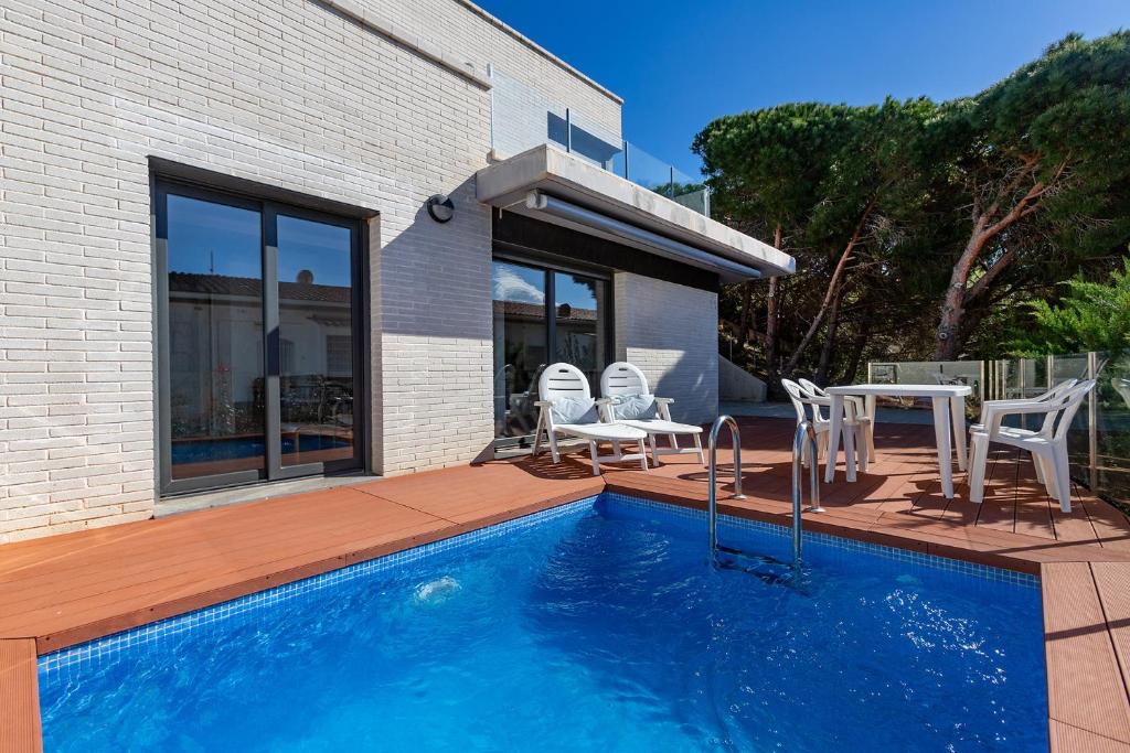 罗萨斯RNET - Casa 4 - Vista Mar Almadrava Roses的房屋旁的游泳池配有椅子和桌子
