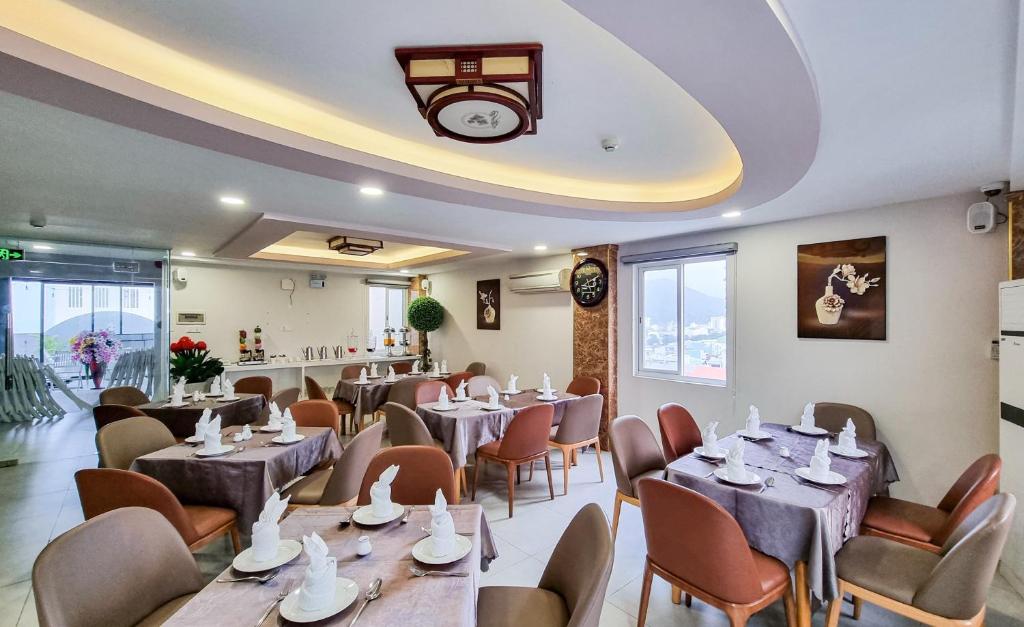 归仁Xavia Hotel Quy Nhơn的餐厅设有桌椅和天花板上的时钟