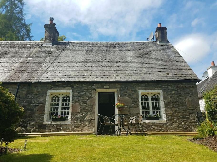 亚历山德里亚Historic cottage next to loch lomond Luss的古老的石头小屋,设有黑色的门和窗户
