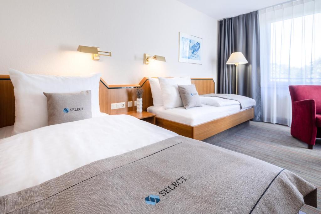 索林根Select Hotel Solingen的酒店客房,配有两张床和椅子