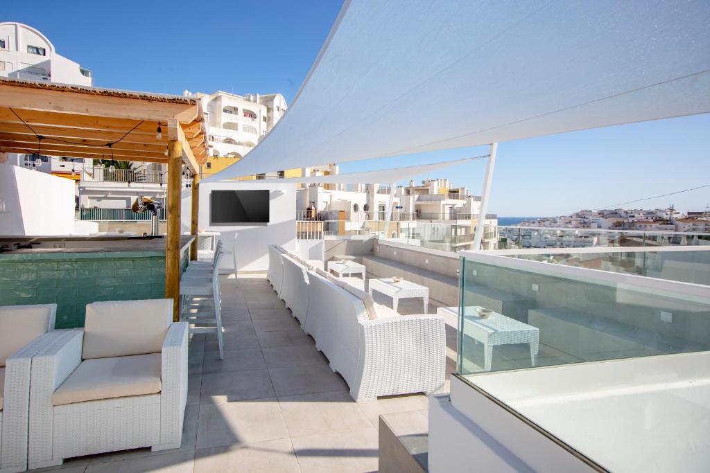阿尔布费拉Sun Lovers Hostel的阳台配有白色椅子,享有城市美景。