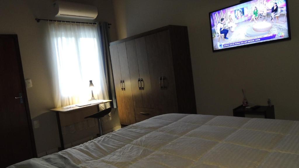 南雅拉瓜Pousada Cusco - no Centro Jaraguá do Sul - Sem Estacionamento的卧室配有一张床,墙上配有电视。