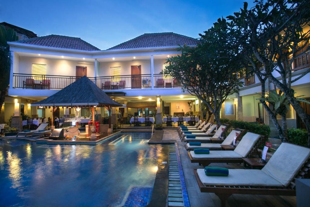 勒吉安尼诗巴厘岛酒店的一个带躺椅的游泳池和一间酒店