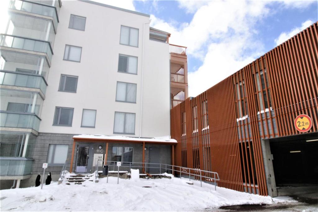 埃斯波Forenom Serviced Apartments Espoo Saunalahti的前面有雪的白色大建筑