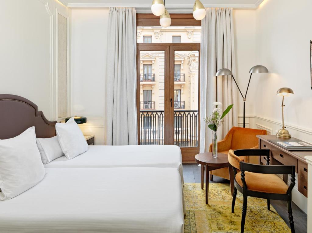马德里女王别墅H10精品酒店的配有一张床和一张书桌的酒店客房
