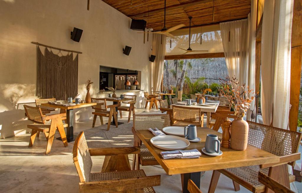 图卢姆Hotel Muaré & Spa Tulum的一间带木桌和椅子的餐厅以及庭院