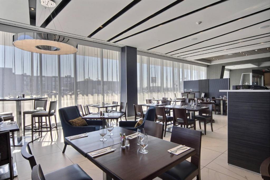 魁北克市魁北克万怡酒店的餐厅设有桌椅和大窗户。