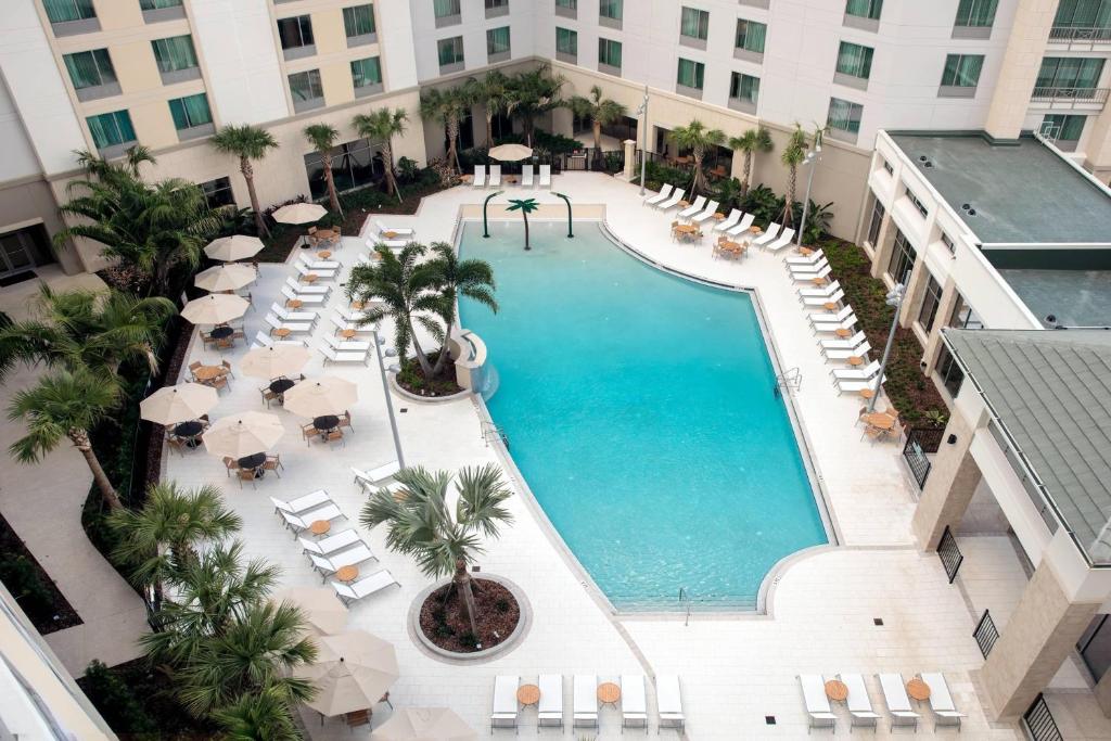 奥兰多SpringHill Suites by Marriott Orlando Theme Parks/Lake Buena Vista的享有酒店游泳池的顶部景色,设有椅子和遮阳伞