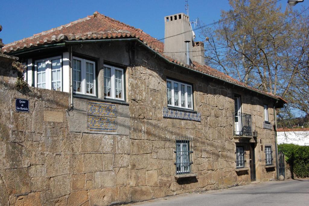 维拉·雷阿尔卡萨达奎因塔马丁霍酒店的街道上一座带白色窗户的古老石头建筑
