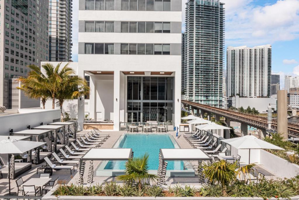 迈阿密Element Miami Brickell的一个带椅子和遮阳伞的游泳池和一座建筑