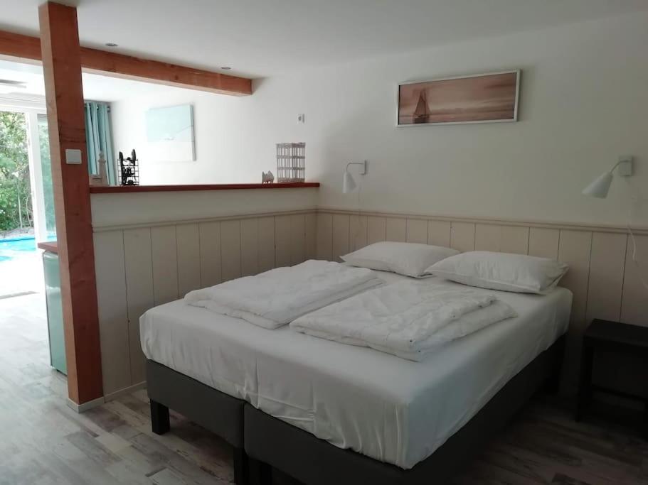 卡兰茨奥赫Strandhuisje DAAN dicht bij zee en strand的卧室内的一张带白色床单和枕头的床