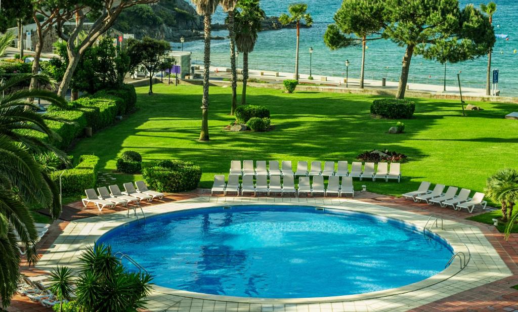 萨卡罗萨加罗健康水疗酒店的一个带椅子的游泳池,背景是大海