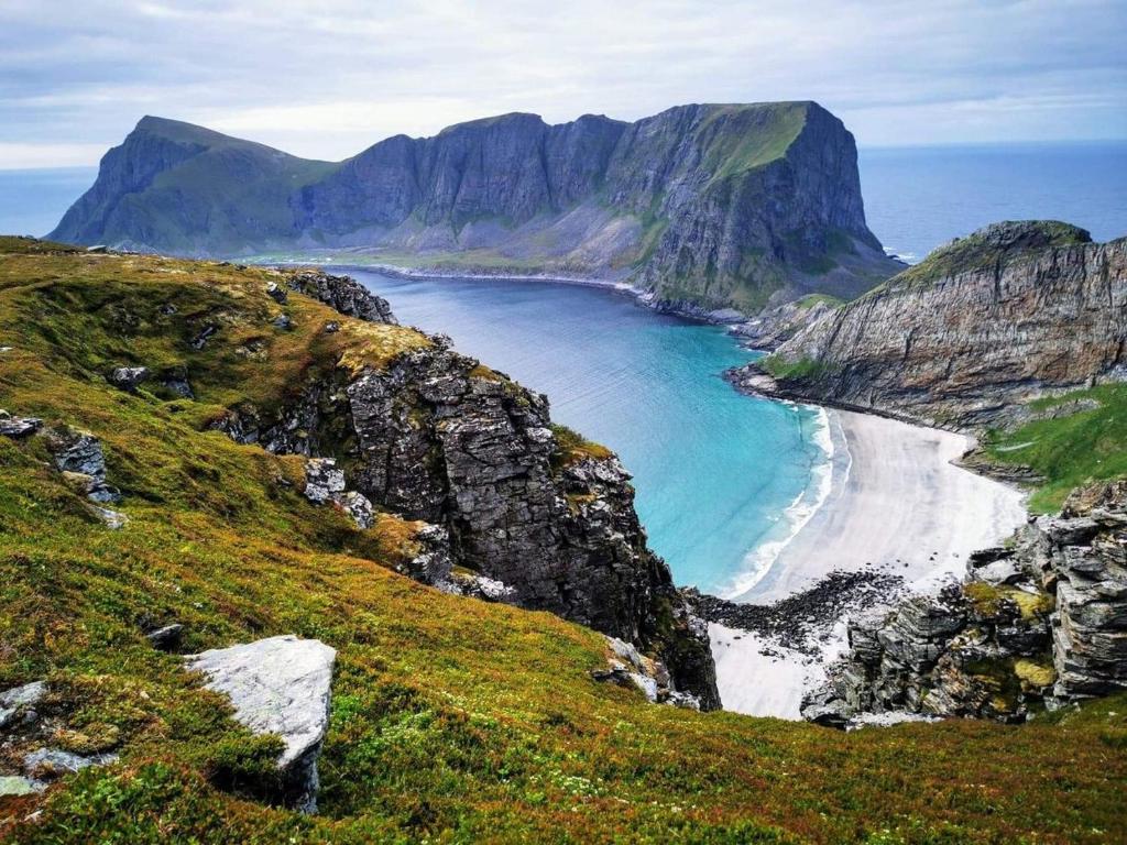 VærøyLofoten Værøy Bryggehotell AS的蓝水山边的海滩