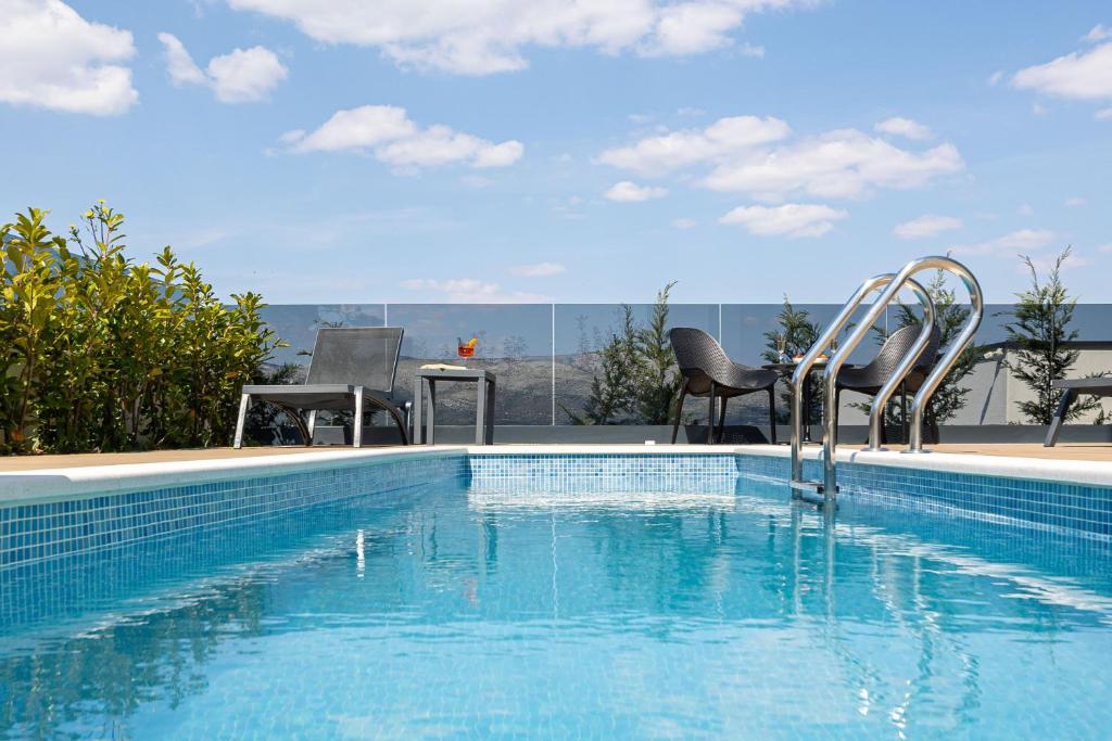 特罗吉尔Villas Residence 360的一个带两把椅子和一张桌子的游泳池