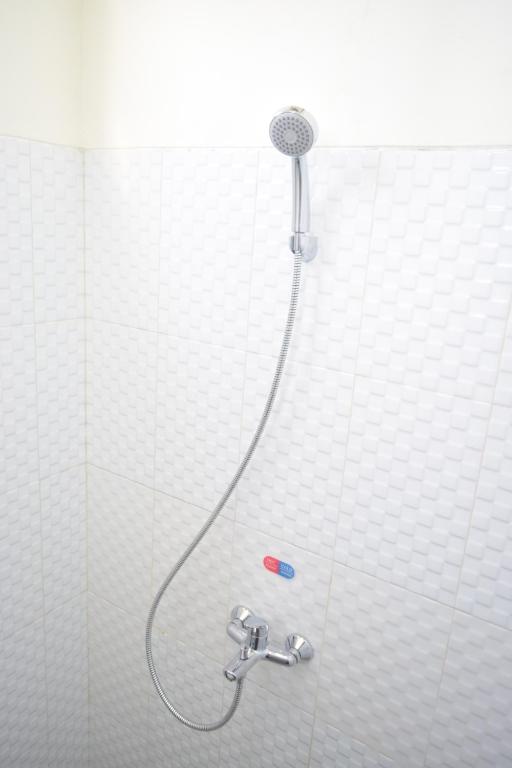 日惹The Cabin Hotel Ambasador的白色瓷砖浴室设有淋浴和软管