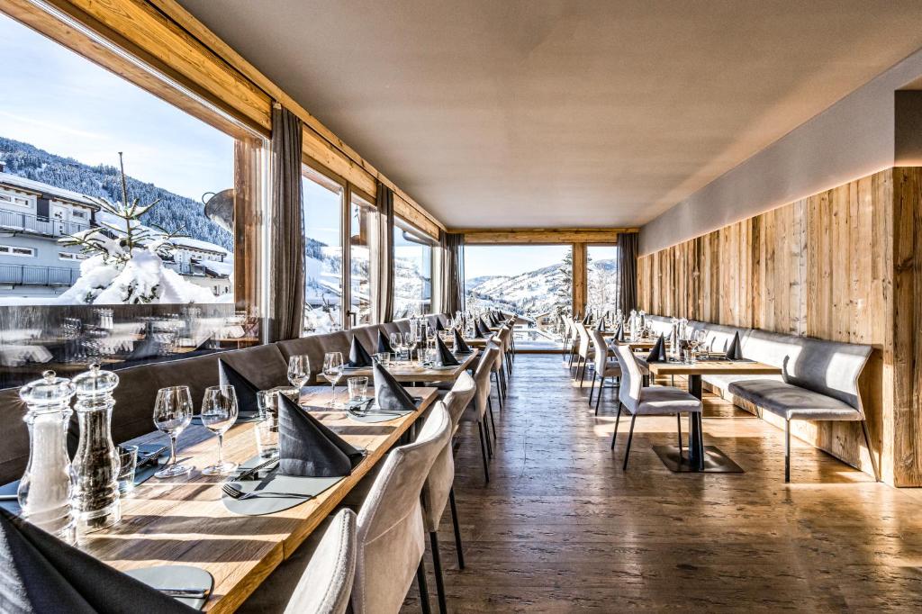 瓦格赖恩ALMMONTE SENSUM SUITES Boutique Hotel的餐厅配有桌椅,位于山脉的背景中