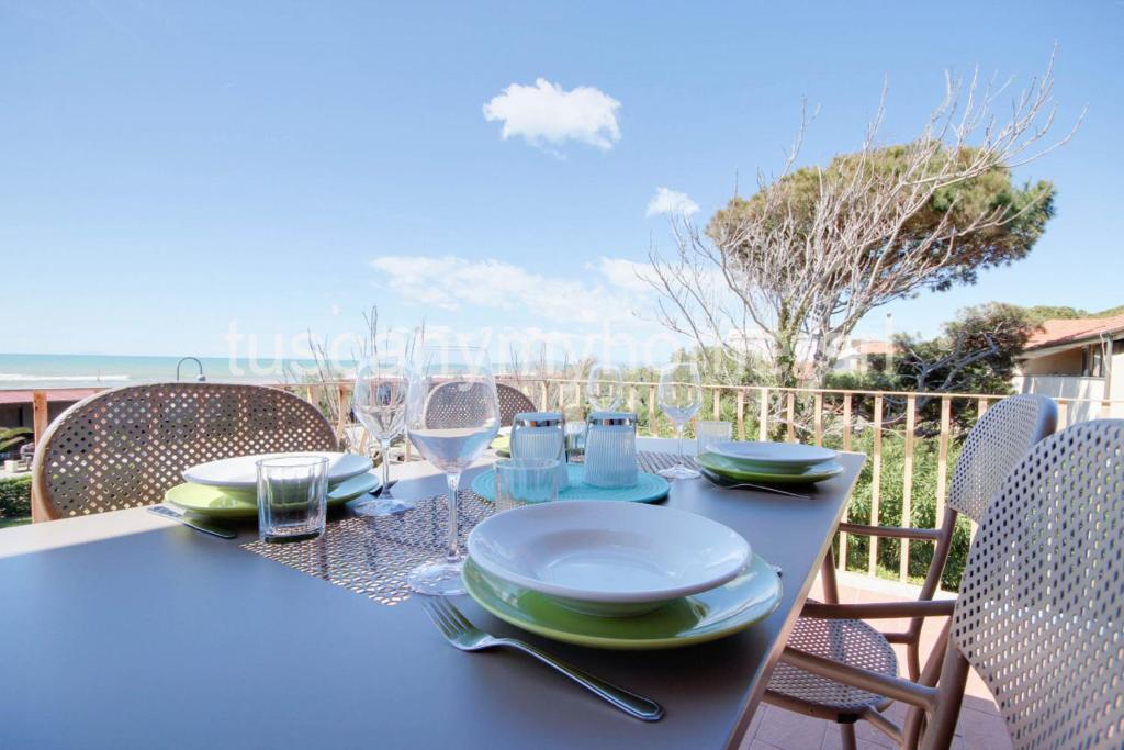 卡斯蒂里昂纳·德拉佩VELA terrazza sul mare con 2 camere e parcheggio的阳台上的桌子上摆放着盘子和酒杯