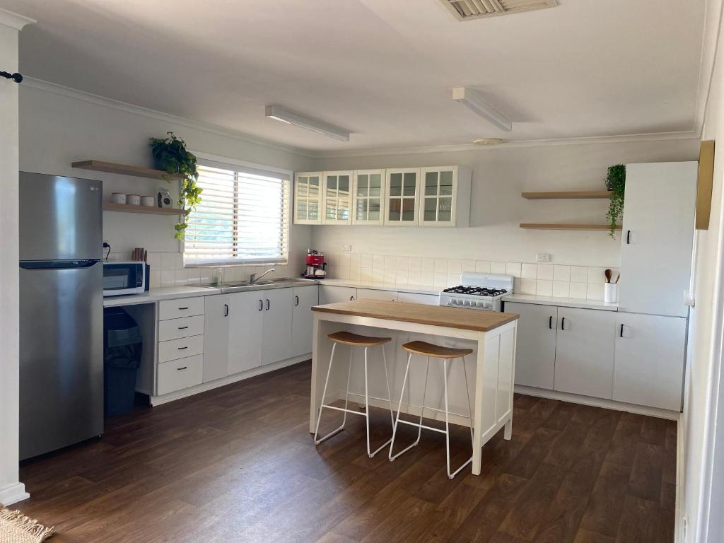Country retreat的一间厨房,配有白色橱柜和一个带凳子的厨房岛