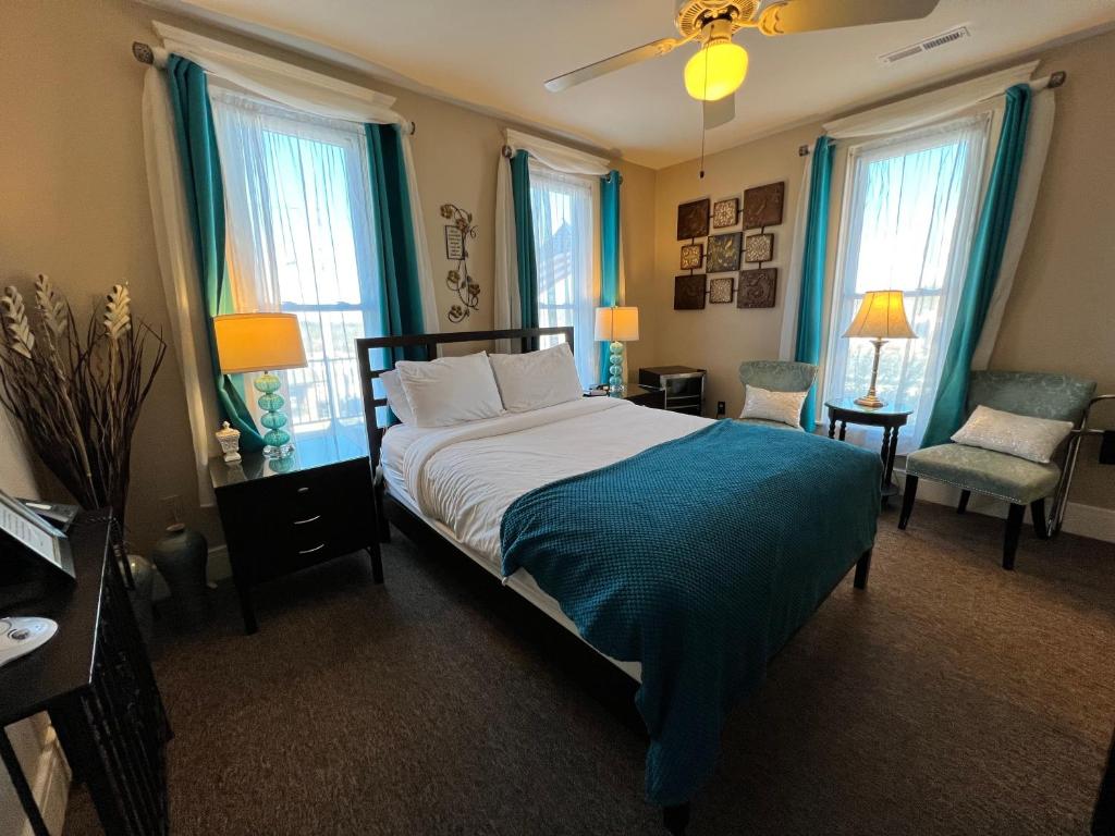 布兰森Historic Branson Hotel - Serendipity Room with Queen Bed - Downtown - FREE TICKETS INCLUDED的一间卧室配有一张带蓝色窗帘的大床