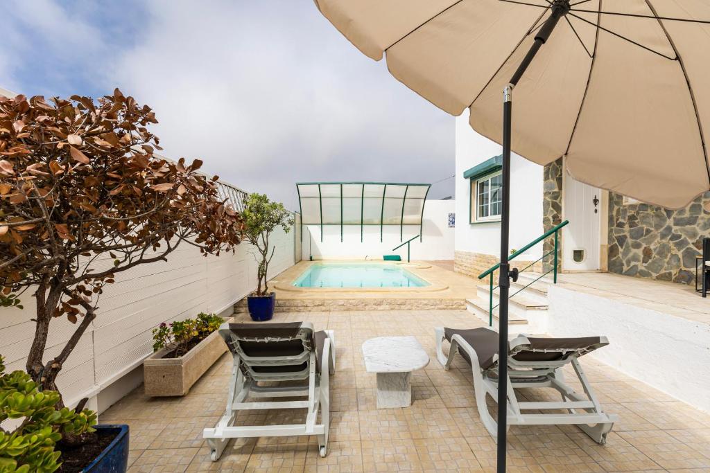 埃里塞拉Spacious 3 bedroom house w/ swimming pool的一个带椅子和遮阳伞的庭院和一个游泳池