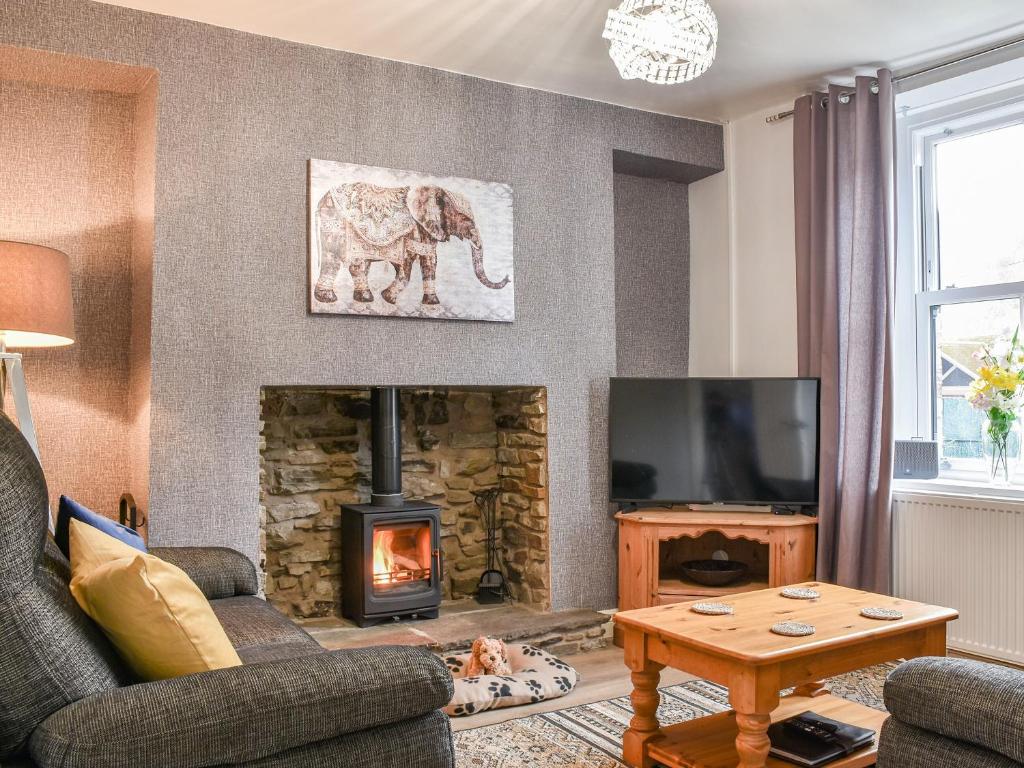 CrosskeysCwmcarn Cottage的客厅设有壁炉,墙上挂着大象照片