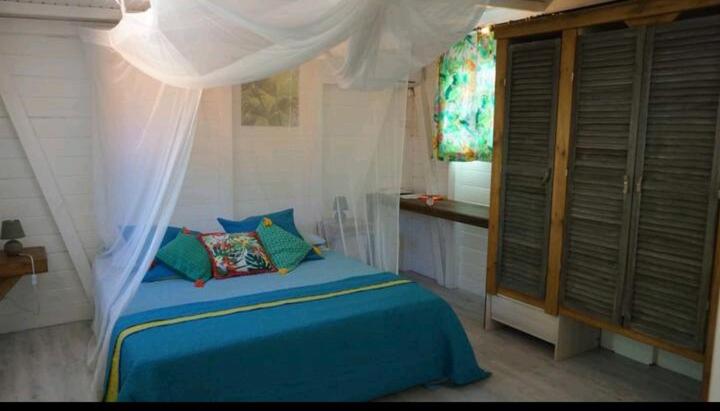 莱斯巴斯Le grand palm gîte filao的一间卧室设有蓝色的床和窗户。