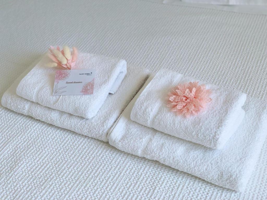 波多河丽Fairy home Porto Heli的床上的两条毛巾和一朵花