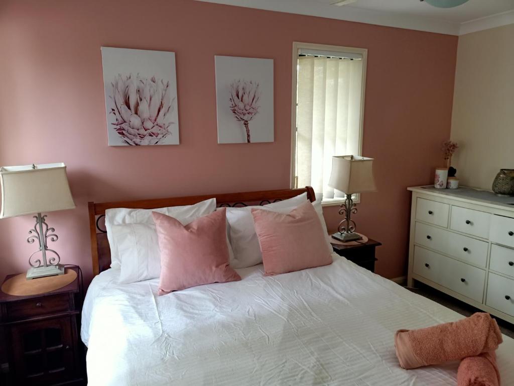 布里斯班Tingalpa Townhouse Treat的卧室配有白色床和粉红色枕头