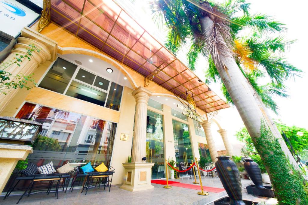 胡志明市Sunshine Boutique Hotel Phu My Hung的一座带椅子和棕榈树的建筑