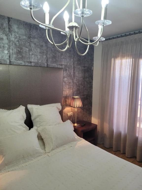 格拉纳达Privada Confort Granada的卧室配有一张白色大床和吊灯。