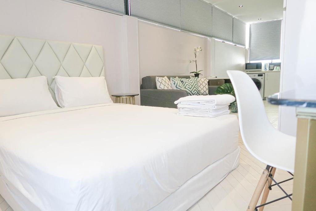 新加坡Comfy Studio 7 by ReCharge的白色卧室配有一张大床和椅子