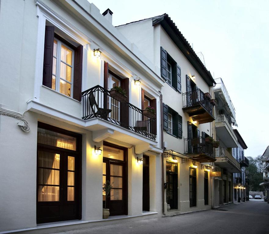 纳夫普利翁伊斯尼佩西恩酒店的白色的建筑,设有窗户和阳台,位于街道上