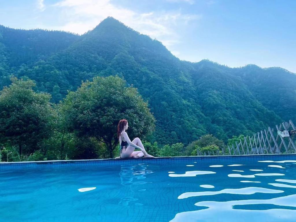 张家界Zhangjiajie National Park Nvue Resorts的坐在游泳池边缘的女人