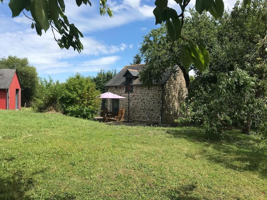 蒙特多尔Maisonnette au pied du Mont Dol的一座古老的石头房子,在田野里设有红色谷仓